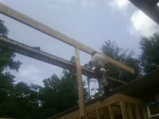 Carpenter setting a ridge beam over a new addition frame — Ice Dam Removal by Roofing Brothers in Gardendale