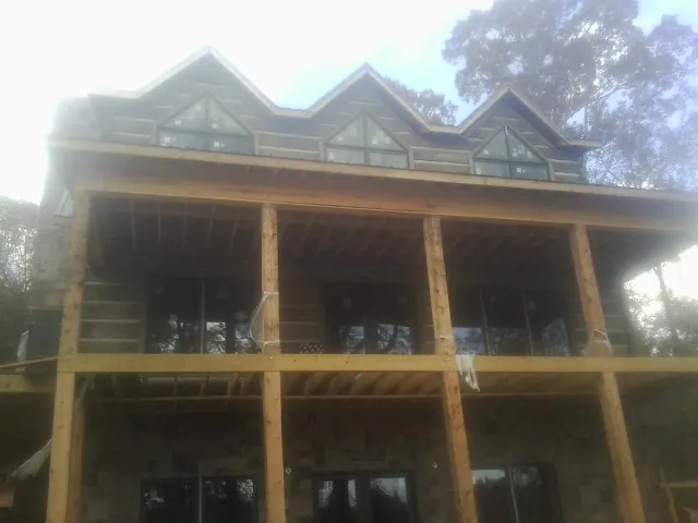 Dormers and porch framing on a large log home under construction — Roof Coating work by our crew in Gardendale