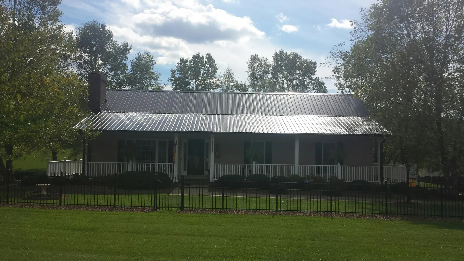 Gray metal roof on a brick ranch with a full width front porch — Gutter Guard Installation work by our crew in Gardendale