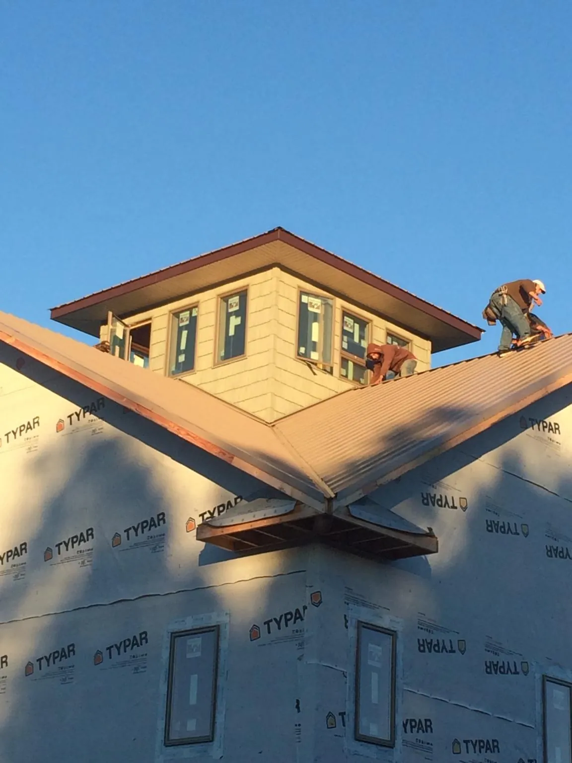 Roofers working around a rooftop cupola on a new metal roof at sunset — Roof Waterproofing in Gardendale by Roofing Brothers